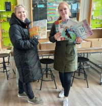 Twee leerkrachten van De Opstap met de gedoneerde boeken